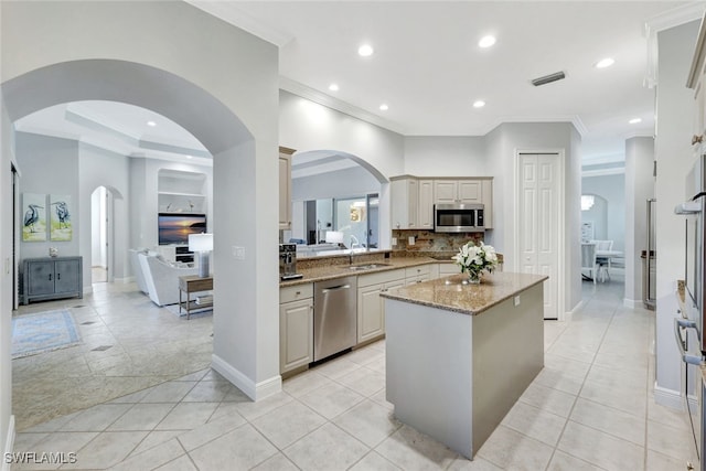 kitchen with a center island, sink, stainless steel appliances, light stone counters, and light tile patterned floors