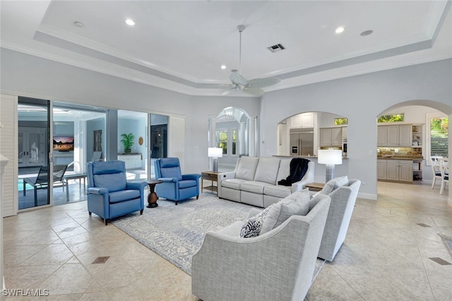 living room with a tray ceiling, ceiling fan, and ornamental molding