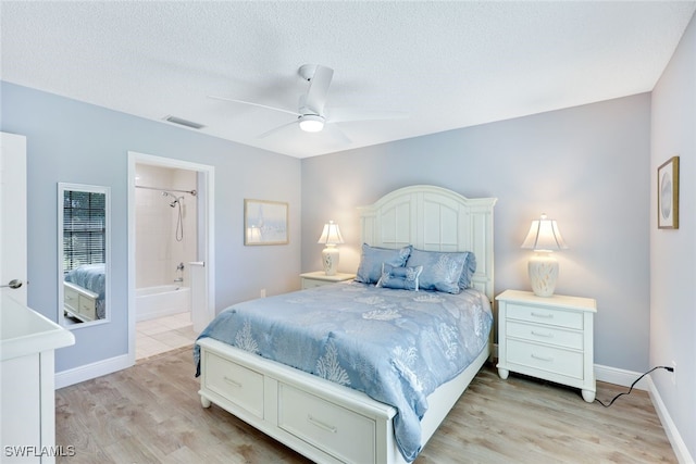 bedroom featuring ceiling fan, light hardwood / wood-style floors, a textured ceiling, and ensuite bath