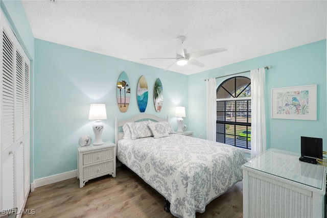 bedroom with ceiling fan, wood-type flooring, a textured ceiling, and a closet