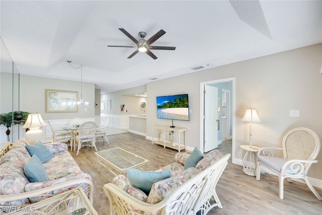 living room with a textured ceiling, ceiling fan with notable chandelier, and hardwood / wood-style flooring