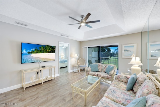 living room featuring hardwood / wood-style floors, a textured ceiling, a raised ceiling, and ceiling fan