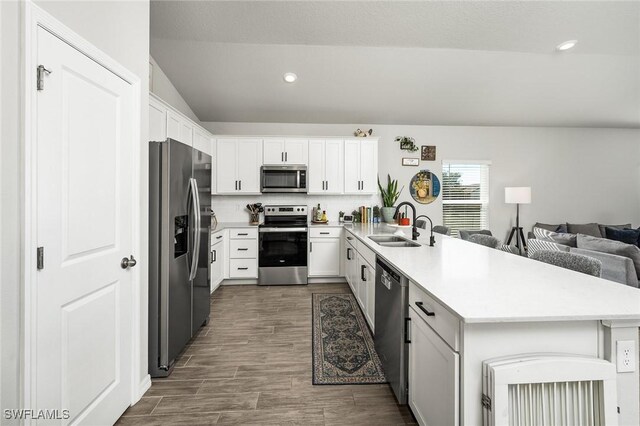 kitchen with sink, dark hardwood / wood-style flooring, kitchen peninsula, stainless steel appliances, and white cabinets