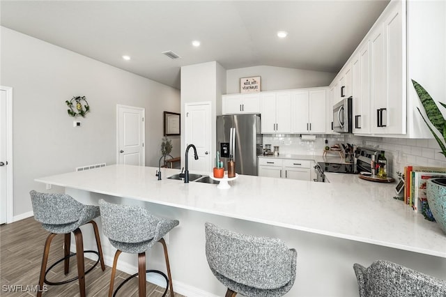 kitchen featuring tasteful backsplash, kitchen peninsula, white cabinets, and appliances with stainless steel finishes