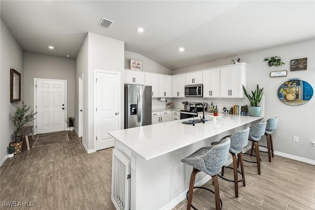 kitchen with backsplash, white cabinets, sink, kitchen peninsula, and stainless steel appliances