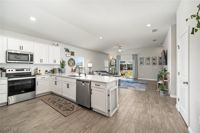 kitchen featuring white cabinets, kitchen peninsula, sink, and appliances with stainless steel finishes