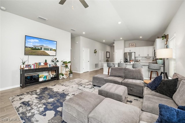 living room featuring ceiling fan, light wood-type flooring, and lofted ceiling