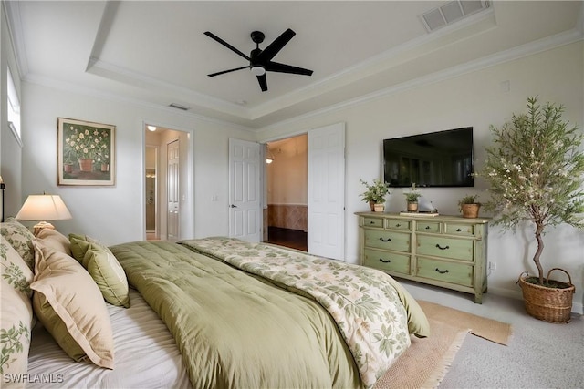 carpeted bedroom with ensuite bathroom, ceiling fan, a raised ceiling, and crown molding