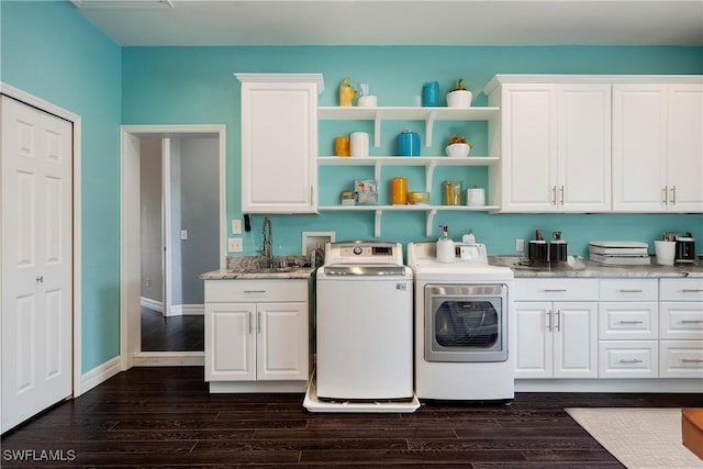 laundry area with cabinets, dark hardwood / wood-style floors, washing machine and dryer, and sink