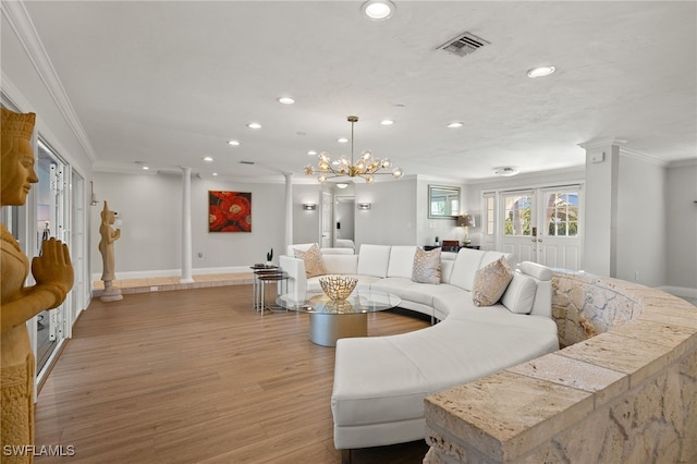 living room featuring a notable chandelier, ornamental molding, light hardwood / wood-style floors, french doors, and ornate columns