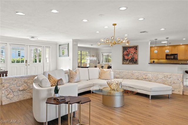 living room with crown molding, a notable chandelier, and light hardwood / wood-style flooring