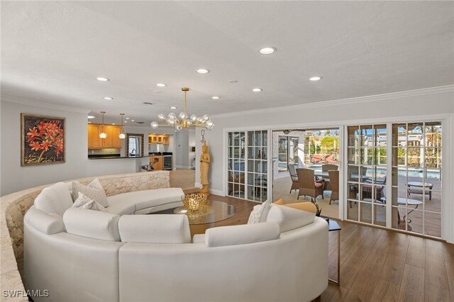 living room featuring an inviting chandelier, crown molding, and wood-type flooring