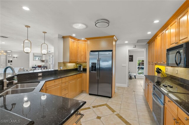 kitchen with sink, light tile patterned floors, appliances with stainless steel finishes, decorative light fixtures, and dark stone counters