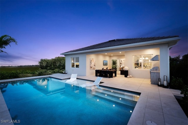 pool at dusk with a patio area