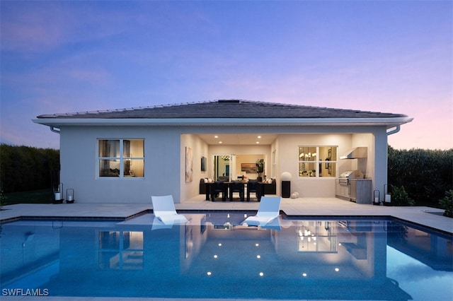 pool at dusk featuring area for grilling and a patio