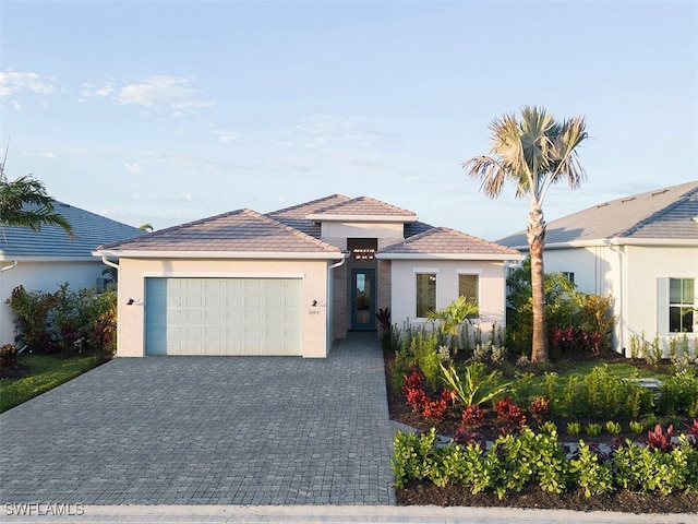 view of front of property featuring a garage, a tiled roof, decorative driveway, and stucco siding