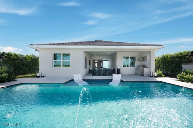 back of property featuring exterior kitchen, a patio area, a fenced in pool, and stucco siding