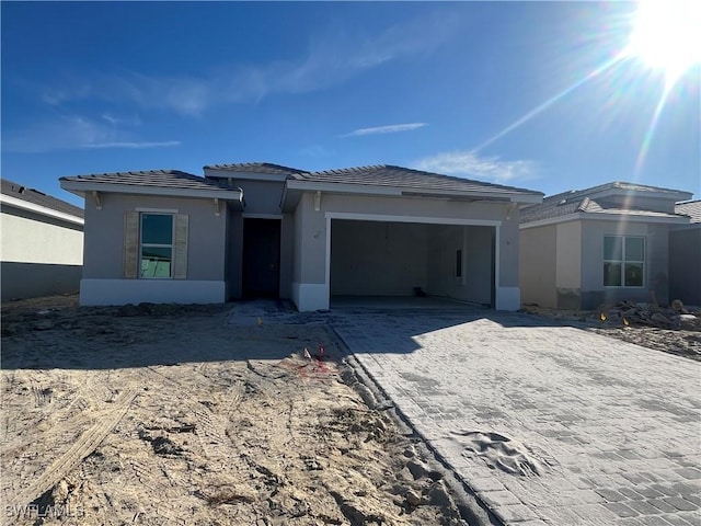 view of front of property featuring decorative driveway, an attached garage, and stucco siding