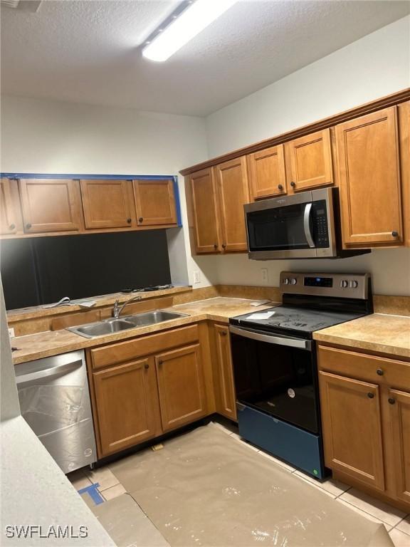 kitchen featuring light tile patterned flooring, sink, and appliances with stainless steel finishes