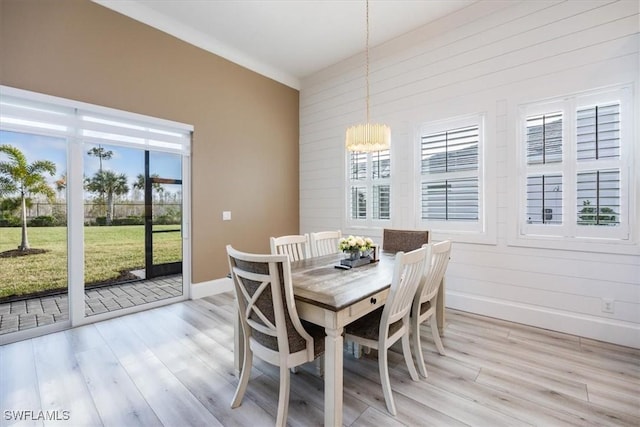 dining room with wood walls, light hardwood / wood-style flooring, and an inviting chandelier