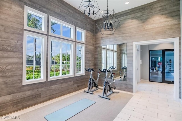 exercise area with light tile patterned flooring, a high ceiling, and a notable chandelier