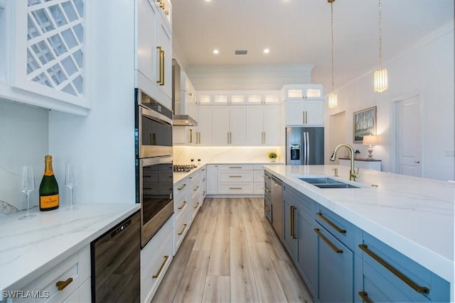 kitchen with white cabinets, sink, hanging light fixtures, light stone counters, and stainless steel appliances