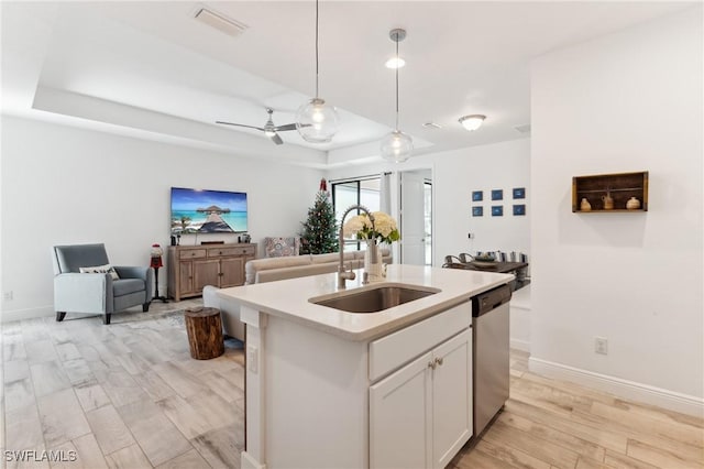 kitchen with a sink, open floor plan, light countertops, stainless steel dishwasher, and a center island with sink