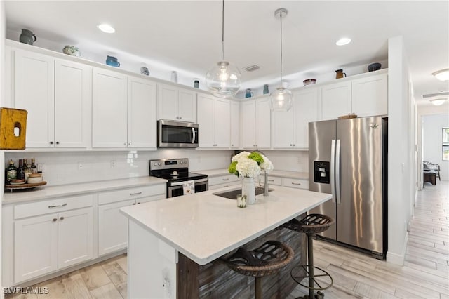 kitchen with white cabinetry, decorative light fixtures, and appliances with stainless steel finishes