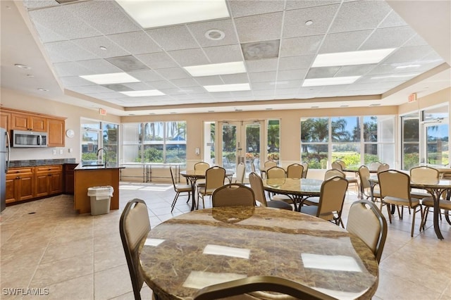 tiled dining room with sink, a paneled ceiling, and french doors