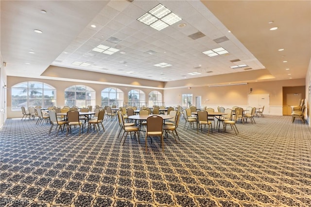 carpeted dining space with a paneled ceiling