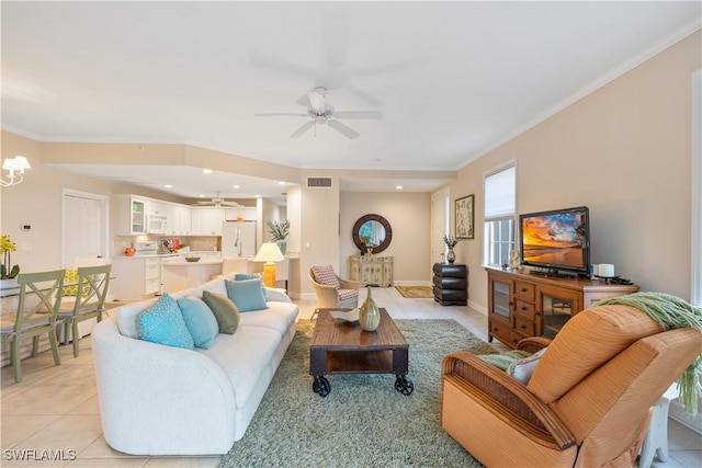 tiled living room with ceiling fan with notable chandelier and crown molding