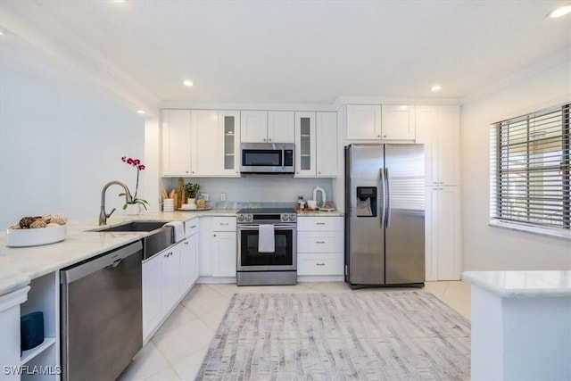 kitchen featuring stainless steel appliances, light tile patterned flooring, a sink, and white cabinetry