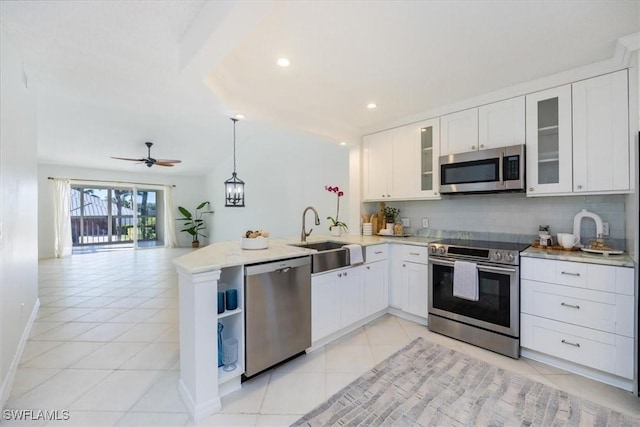 kitchen with appliances with stainless steel finishes, light tile patterned flooring, a sink, and a peninsula