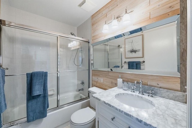 bathroom with enclosed tub / shower combo, visible vents, vanity, and toilet