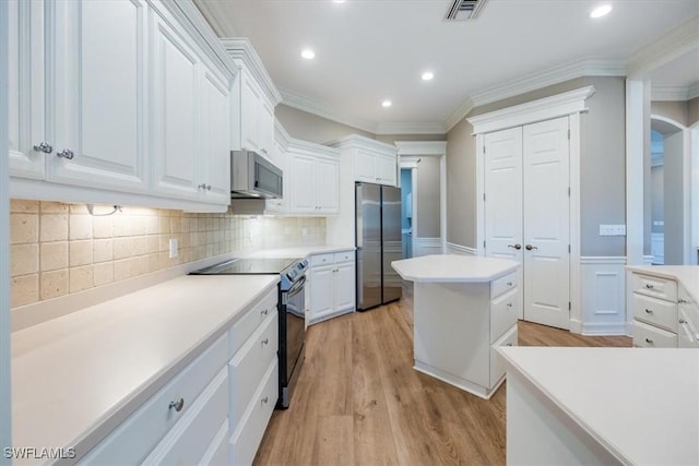 kitchen featuring white cabinetry, light hardwood / wood-style flooring, crown molding, decorative backsplash, and appliances with stainless steel finishes