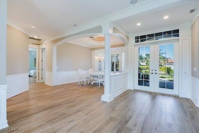 foyer entrance featuring crown molding, french doors, a chandelier, and light wood-type flooring