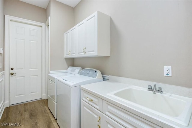 washroom with hardwood / wood-style floors, washer and dryer, cabinets, and sink