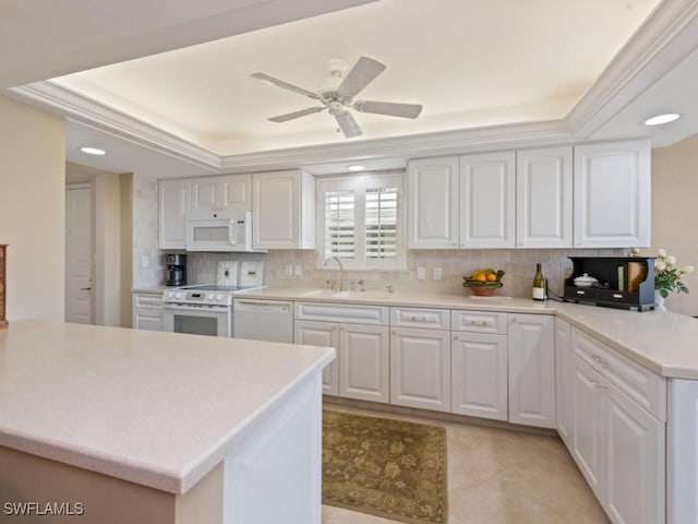 kitchen featuring a raised ceiling, white appliances, white cabinetry, and kitchen peninsula