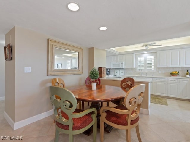 tiled dining area with ceiling fan and sink