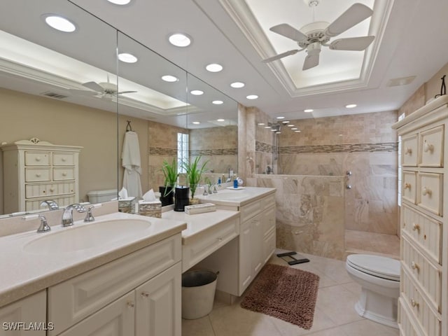 bathroom with toilet, a tile shower, a tray ceiling, and tile patterned floors