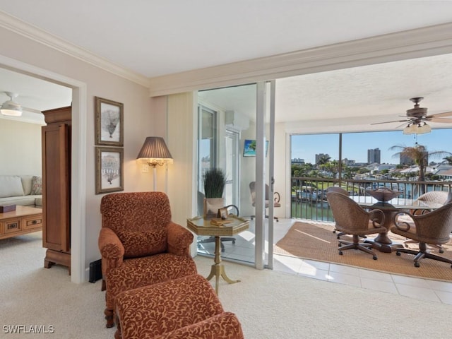 sitting room with light carpet, crown molding, a water view, and ceiling fan