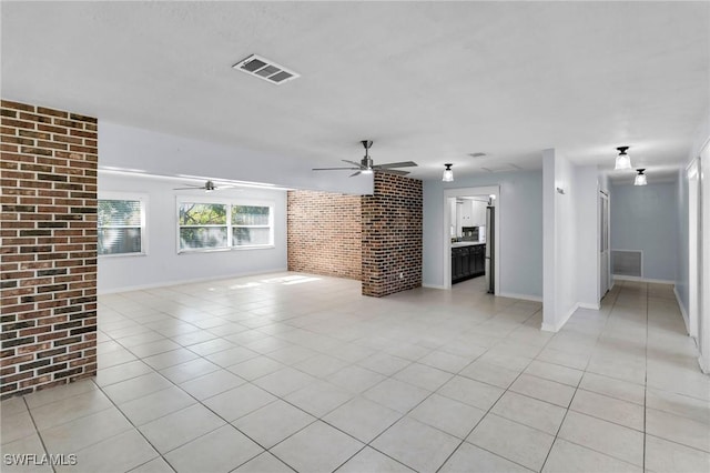 unfurnished living room featuring light tile patterned flooring and brick wall