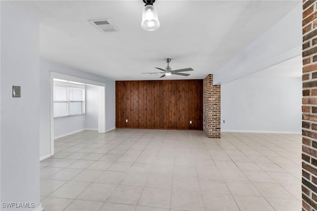 unfurnished living room with ceiling fan and wood walls