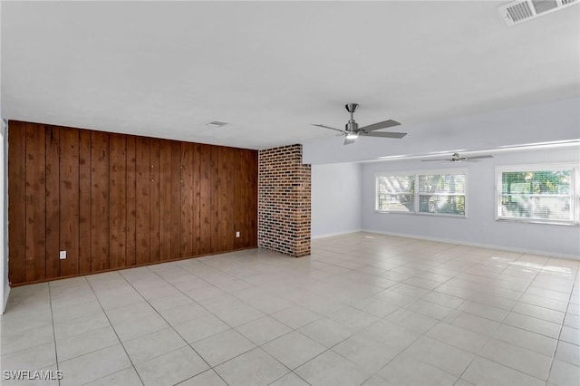 unfurnished living room with ceiling fan, wooden walls, and a brick fireplace