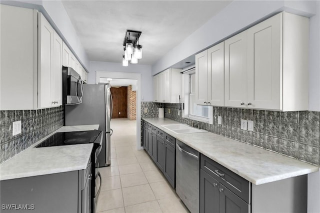 kitchen featuring gray cabinetry, white cabinets, sink, light tile patterned floors, and stainless steel appliances