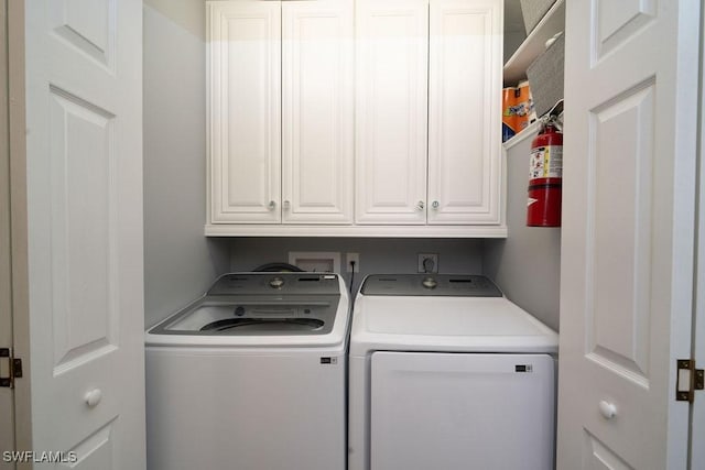 clothes washing area featuring washing machine and dryer and cabinets