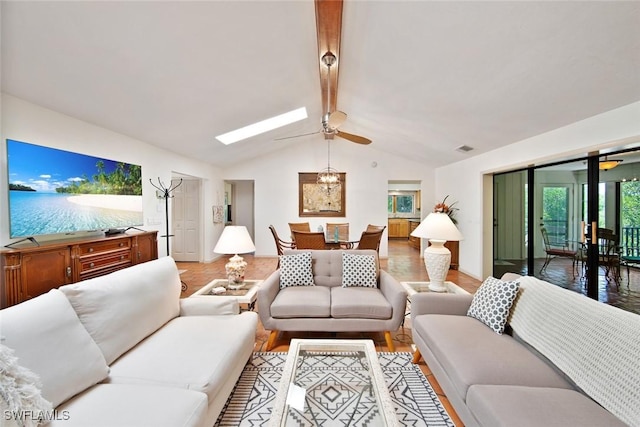 living room with wood-type flooring, ceiling fan, and vaulted ceiling with skylight