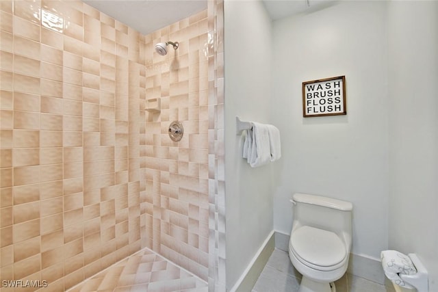 bathroom with toilet, tile patterned flooring, and tiled shower