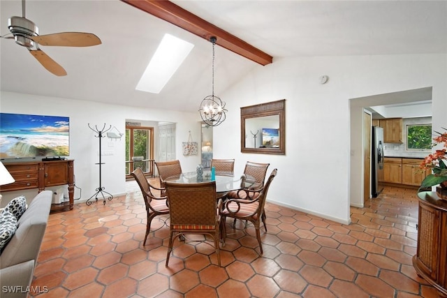 dining room with vaulted ceiling with skylight, ceiling fan with notable chandelier, and dark tile patterned floors