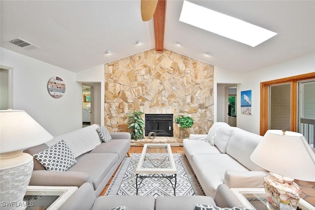 living room featuring a stone fireplace and lofted ceiling with skylight